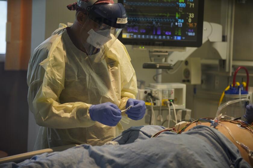 Working inside a negative pressure room on a Covid-19 patient. On the left Alessio Bloesch registered nurse looks over the patients lines at Scripps Mercy Hospital Chula Vista intensive care unit on June 24th, 2020 in Chula Vista. Speaking to doctors, nurses and healthcare staff helping patients with Covid-19 at three South Bay hospitals.