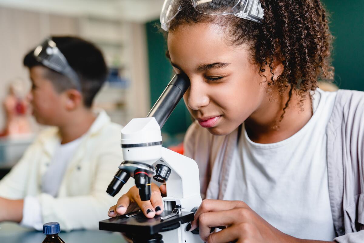 African-american schoolgirl pupil student using working with microscope 
