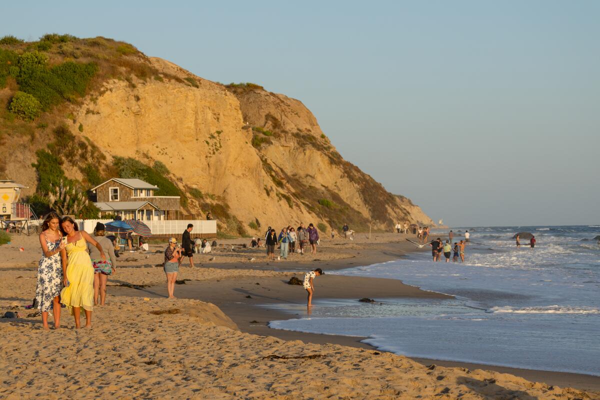 People enjoy the sand and water at Crystal Cove State Beach