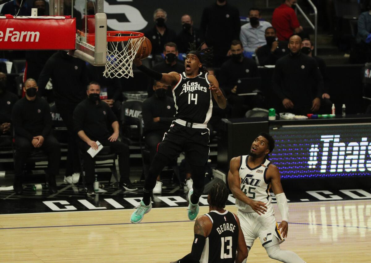 Clippers guard Terance Mann scores on a breakaway against Jazz guard Donovan Mitchell .