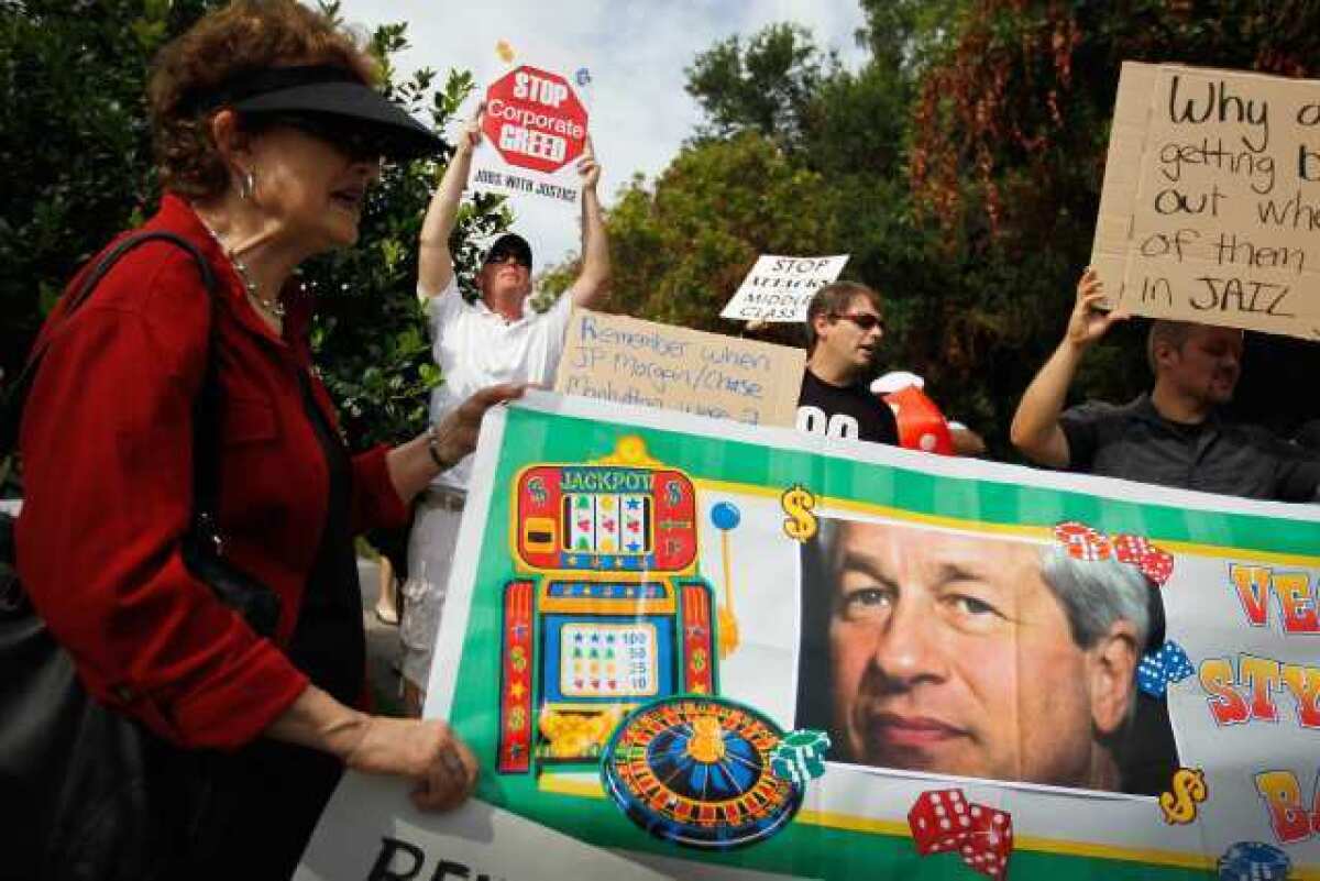 Protesters hold a banner featuring JPMorgan Chairman and CEO Jamie Dimon outside the annual shareholders meeting in Tampa, Fla. JPMorgan Chase, the largest U.S. bank, last week disclosed a $2-billion trading loss.
