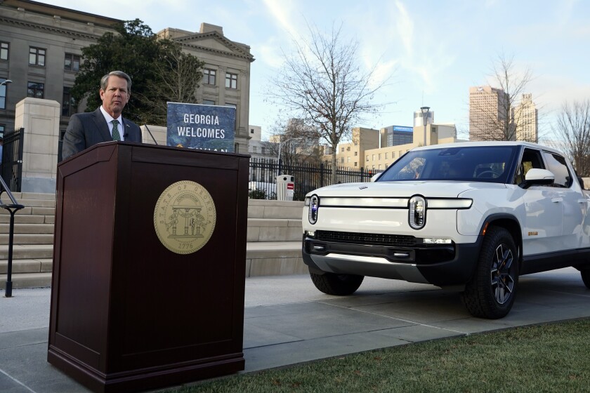 Georgia Gov. Brian Kemp is flanked by a Rivian electric truck announces that the electric truck maker plans to build a $5 billion battery and assembly plant east of Atlanta projected to employ 7,500 workers, Thursday, Dec. 16, 2021, in Atlanta. (AP Photo/John Bazemore)