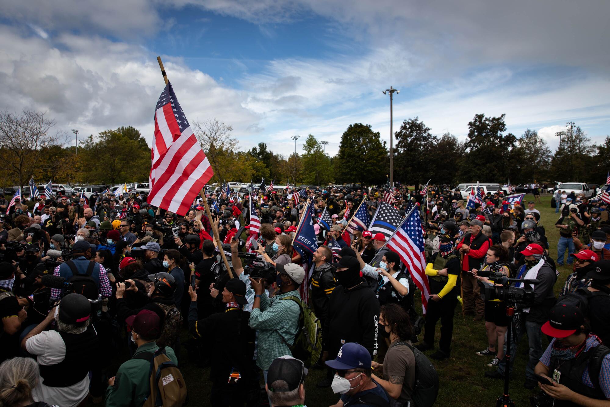 Several hundred members of the Proud Boys in a park raise U.S. and Trump flags