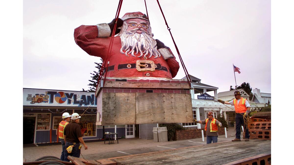 Jan. 27, 2003: Workers lower the Santa statue from the roof of a candy store on Santa Claus Lane in Carpinteria.