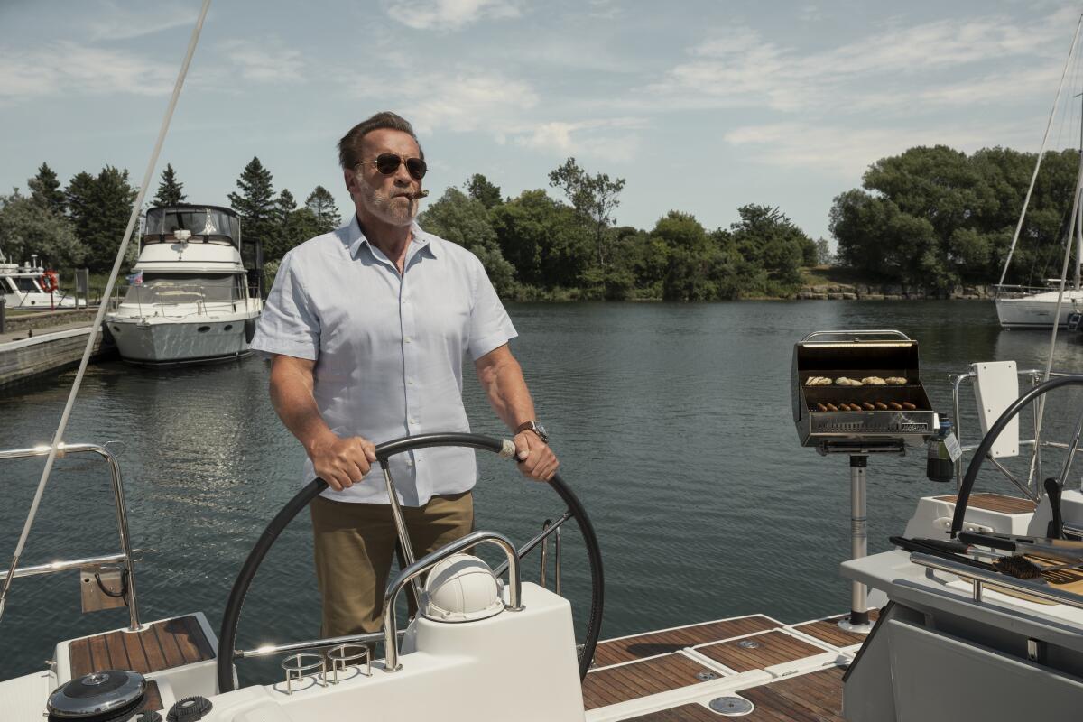 Arnold Schwarzenegger in sunglasses steering a boat