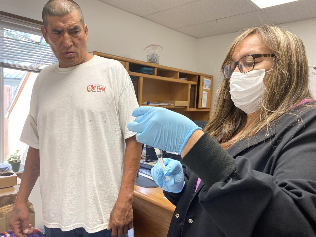 Man winces at vaccination needle held by nurse