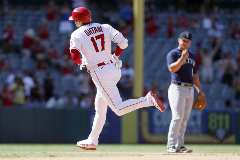 Los Angeles Angels' Shohei Ohtani, left, rounds the bases after hitting a two-run home run, next to Seattle Mariners third baseman Kyle Seager, during the ninth inning of a baseball game in Anaheim, Calif., Sunday, July 18, 2021. (AP Photo/Alex Gallardo)
