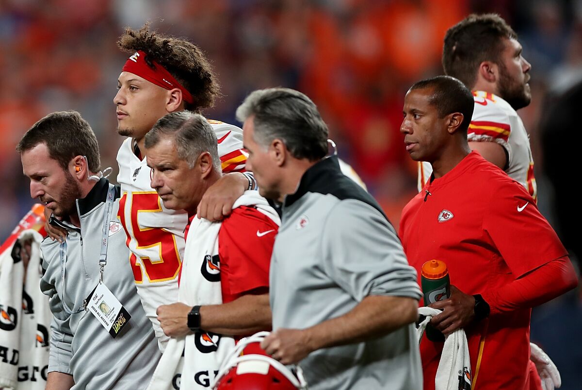 Kansas City Chiefs quarterback Patrick Mahomes is escorted off the field after sustaining a knee injury during the first half against the Broncos.