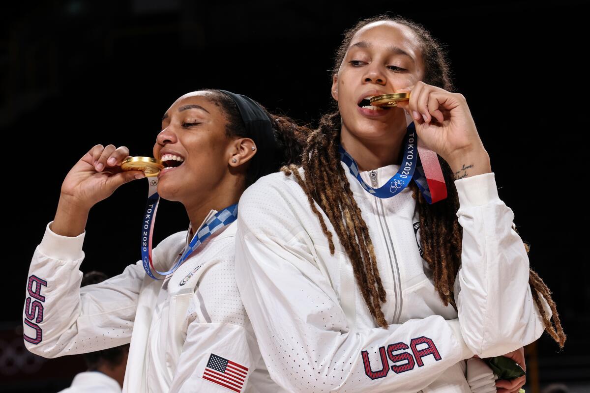 United States forward A'Ja Wilson and Brittney Griner bite their gold medals.