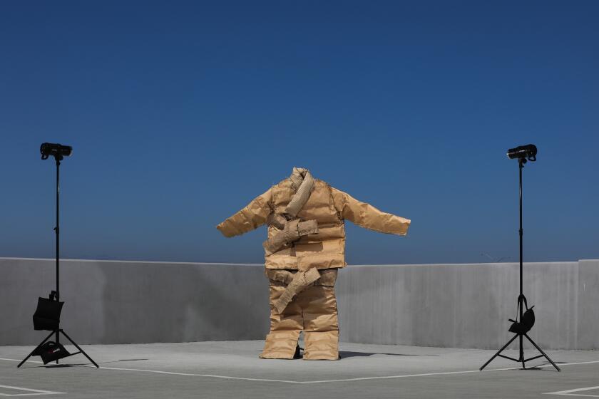 A 10-foot-tall jacket and pants made out of cardboard photographed on top of a concrete parking structure.