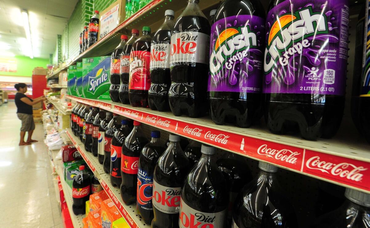 A woman shops for food items near a display of bottles of soda at a supermarket in Rosemead, Calif.