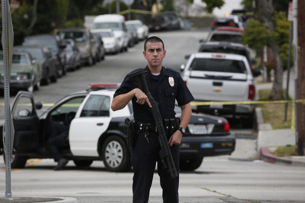 An LAPD officer with a shotgun stops traffic at a roadblock as police search for a gunman or gunmen who opened fire on two detectives outside the LAPD's Wilshire substation.