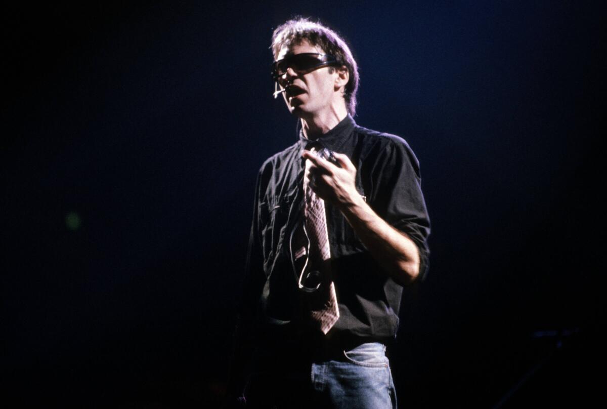 A man onstage in dark glasses 