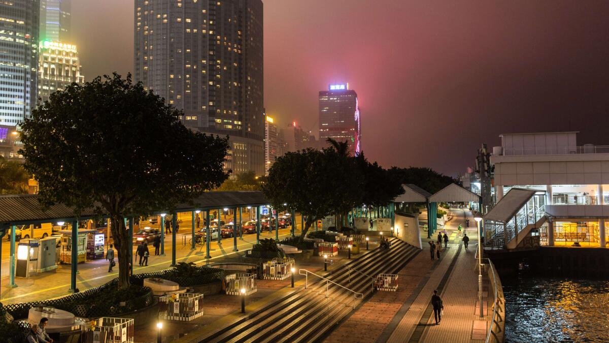 Pedestrians walk on a promenade that runs along Victoria Harbour in Hong Kong. Cathay Pacific is offering a $683 round-trip ticket to Hong Kong from LAX.