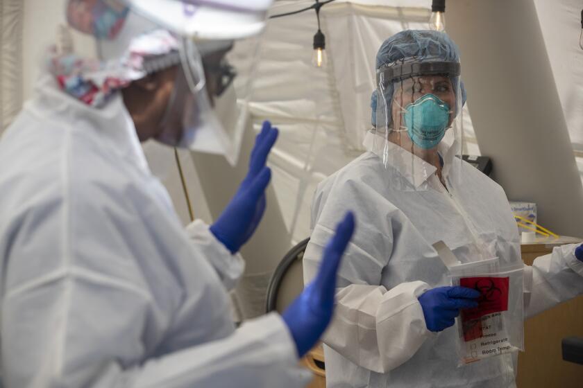 MISSION HILLS, CA - JULY 10: Nurses Janil Wise (CQ), left, and Melinda Gruman, right, talk over testing options for a patient who is pregnant and was exposed to a person with COVID-19, in the OB triage tent at Providence Holy Cross Medical Center on Friday, July 10, 2020 in Mission Hills, CA. (Brian van der Brug / Los Angeles Times)