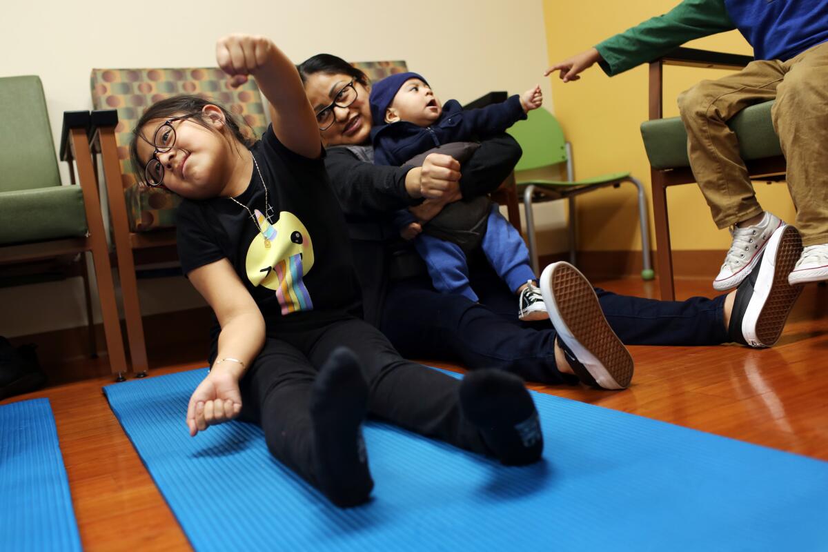 Irie Mazas, 7, with her mother, Miriam Bautista, center, and brother, Carlos Mazas, during a BodyWorks class at Children’s Hospital Los Angeles.