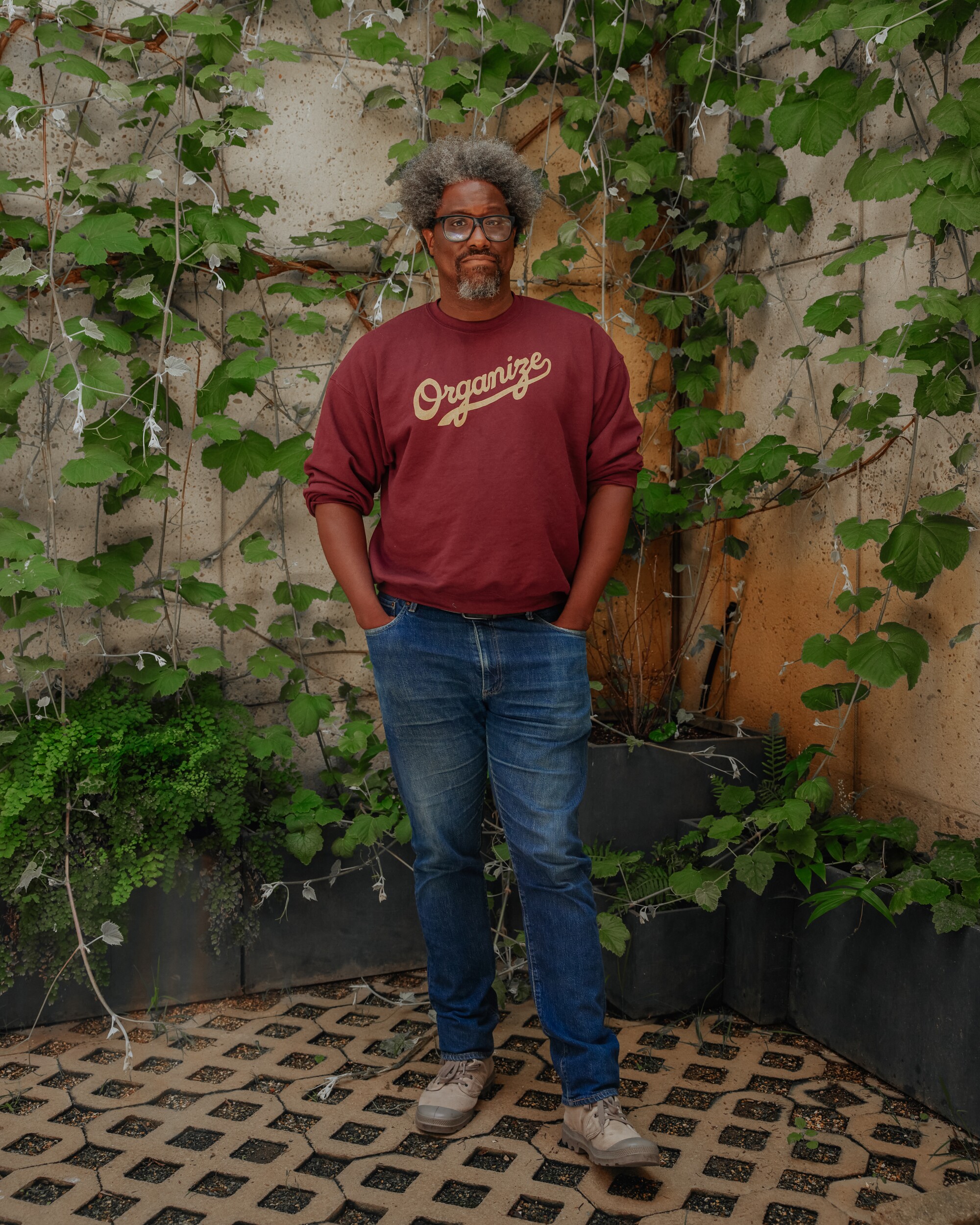 A man in a red sweater in front of a vine wall
