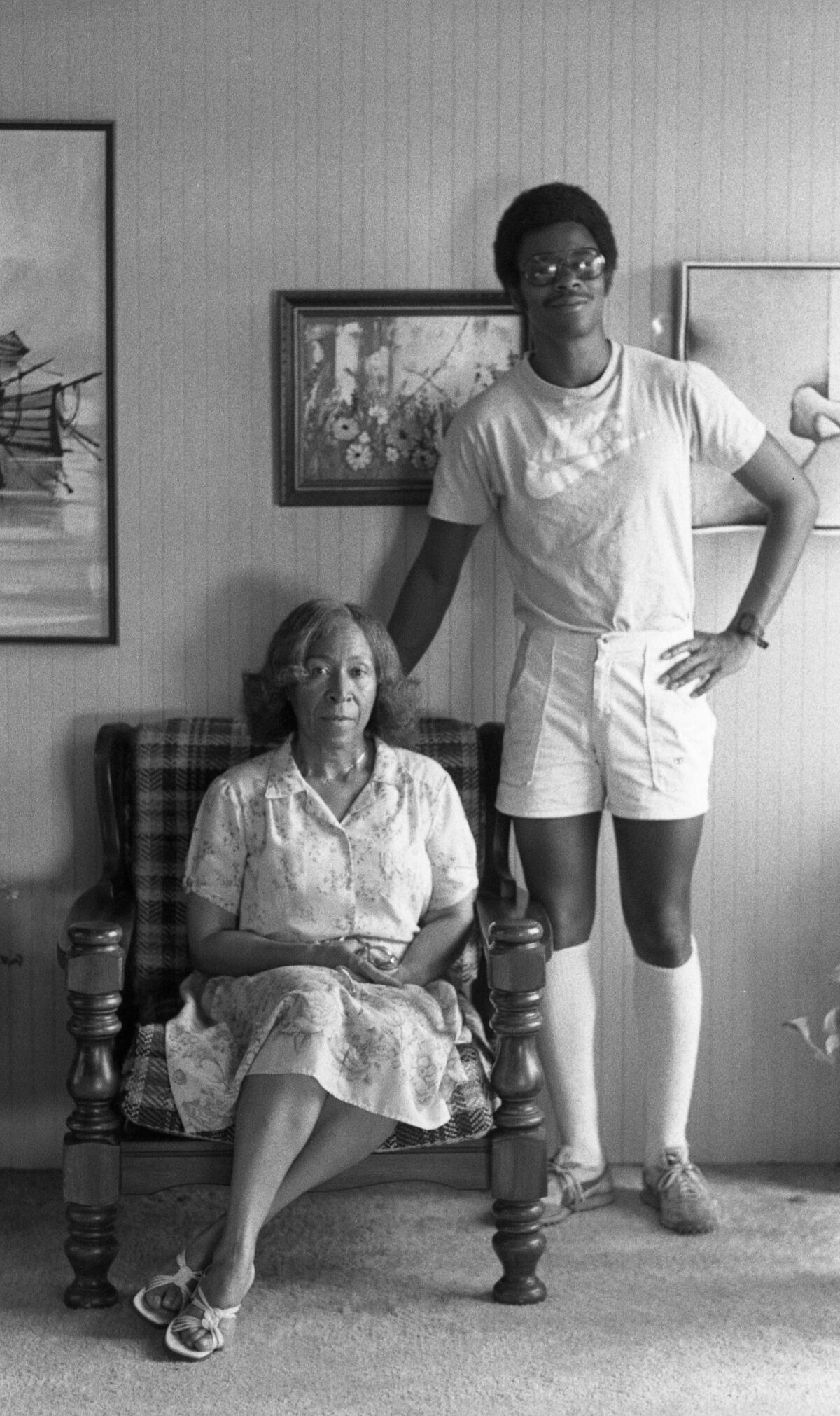 A woman sits in a chair while her son stands beside her