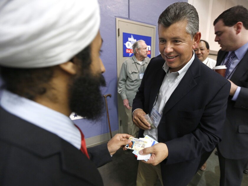 Former Republican Lt. Gov. Abel Maldonado, right, shows his drivers license to monitor Nihal Singh before being allowed to vote for a new party chairman at the California Republican Party convention in Sacramento.