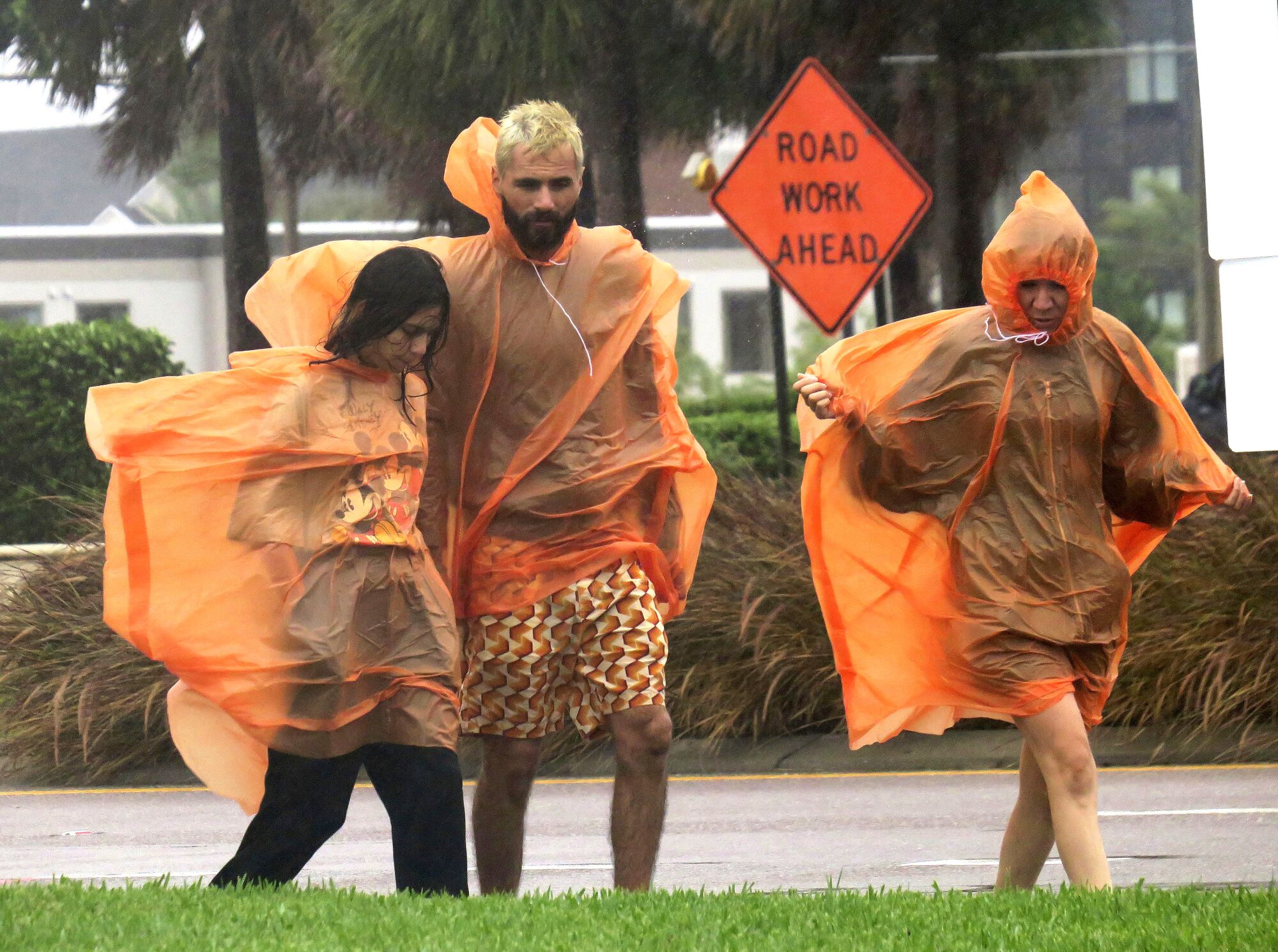 People wearing rain gear walk along a street in Orlando, Fla., amid Hurricane Ian.