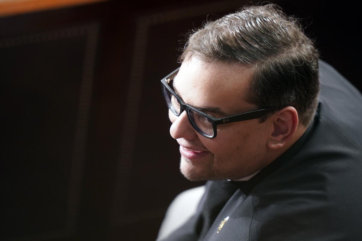 Rep. George Santos looks up and smiles.