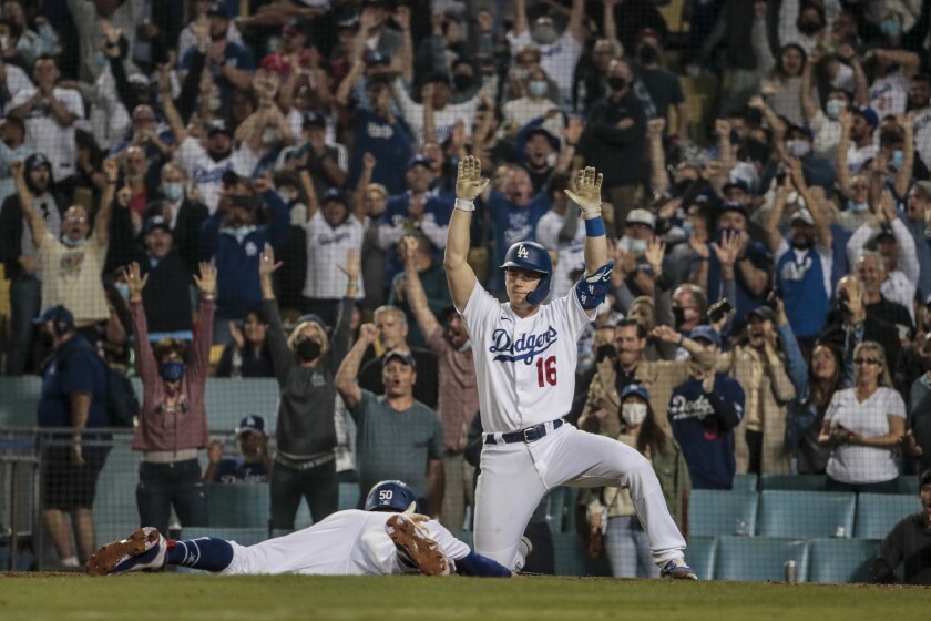 Dodgers catcher Will Smith raises his arms as he greets Mookie Betts, who is sliding headfirst, at the plate