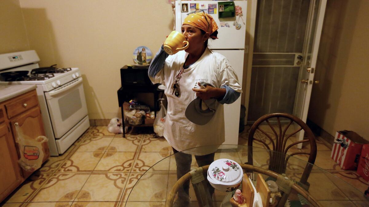 Lourdes Cardenas, 53, after preparing lunch has a cup of coffee before leaving a two-bedroom house she rents with her husband, nephew and five roommates, to pick grapes in Fresno. (Gary Coronado / Los Angeles Times)