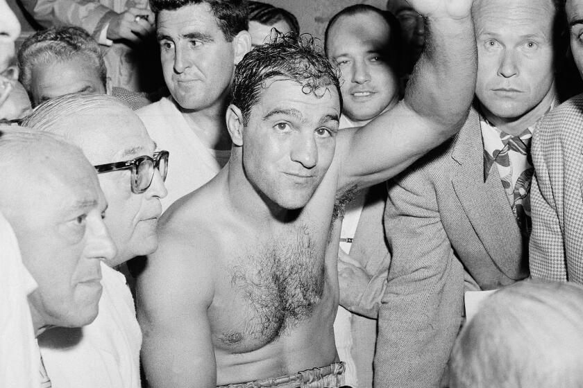 Rocky Marciano raises arm in victory in his dressing room at Yankee Stadium after successfully defending his heavyweight title against Ezzard Charles in New York, June 17, 1954. (AP Photo)