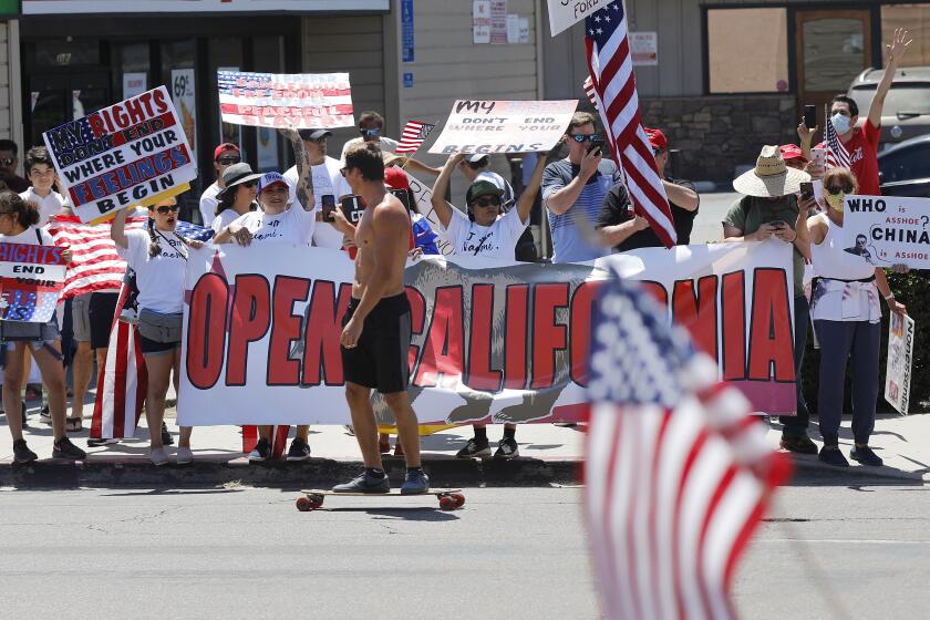 A skateboarder films protesters along Mission Blvd. in Pacific Beach during A Day of Liberty rally on Sunday, April 26, 2020. The protesters were against the government shutdown due to the coronavirus.