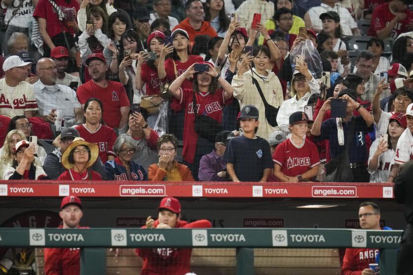 Los Angeles Angels fans take photos of Shohei Ohtani, bottom center, during the seventh inning of a baseball game against the Detroit Tigers in Anaheim, Calif., Saturday, Sept. 16, 2023. (AP Photo/Ashley Landis)
