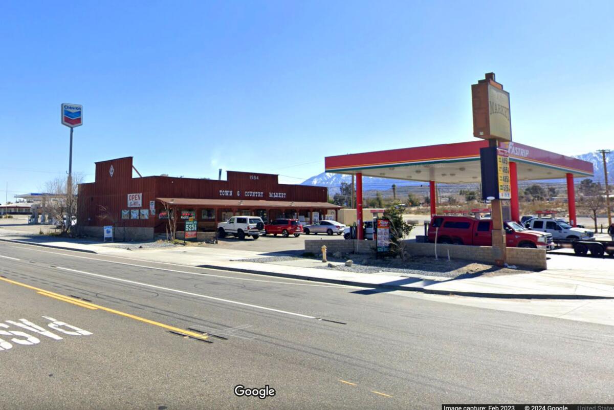 A gas station on the corner of a multilane street next to a low building