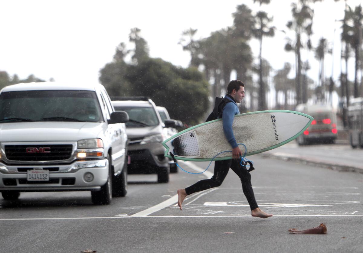 A surfer dashes across Pacific Coast Highway near the Huntington Beach pier. 