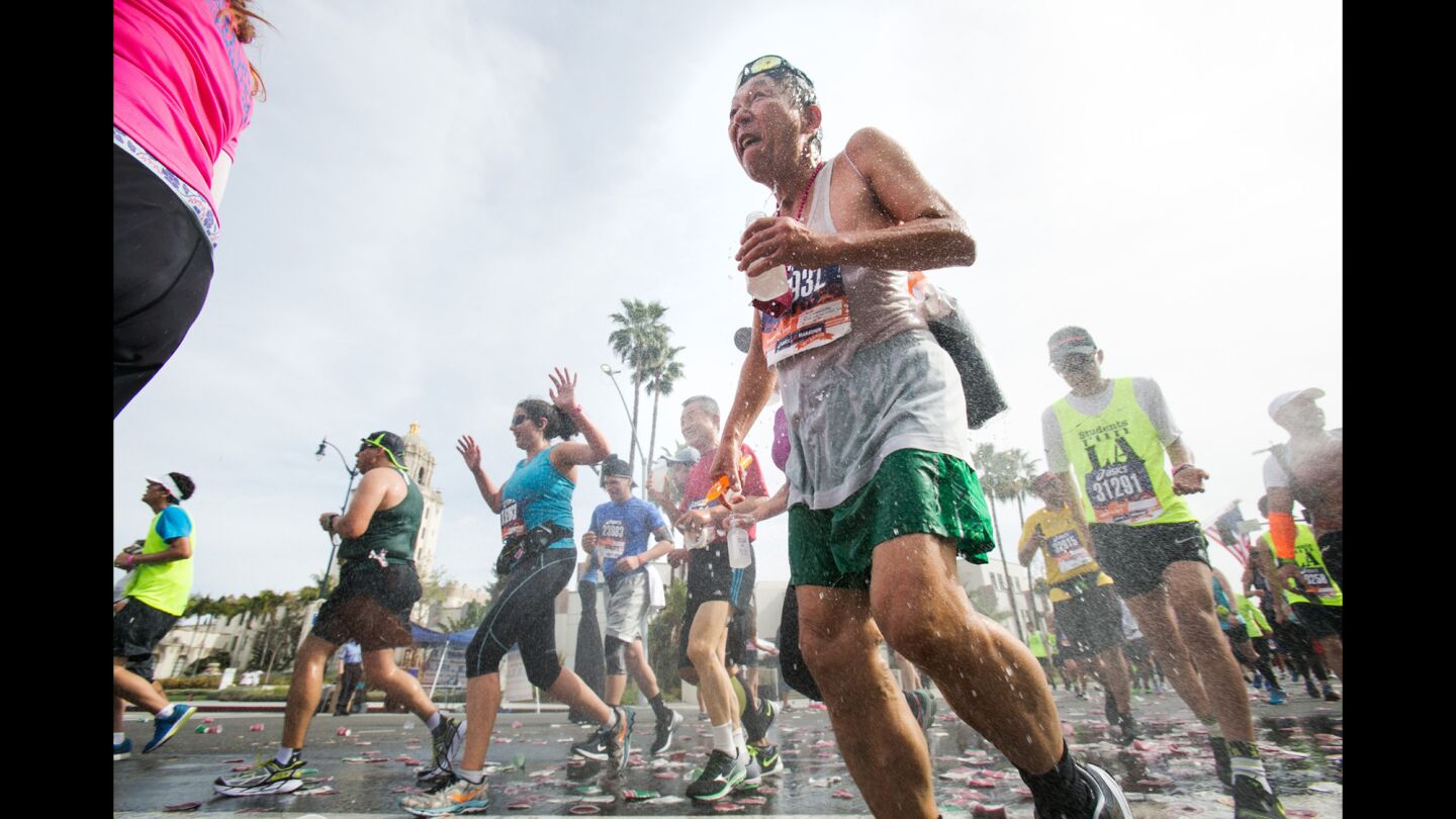 Runners revel in a cold spray of water at mile-marker 16 in Beverly Hills.