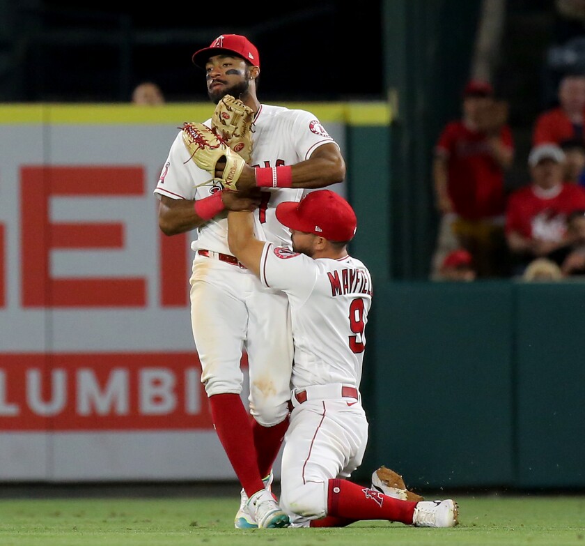 Angels second baseman Jack Mayfield gets tied up with teammate Jo Adell after catching a fly ball.