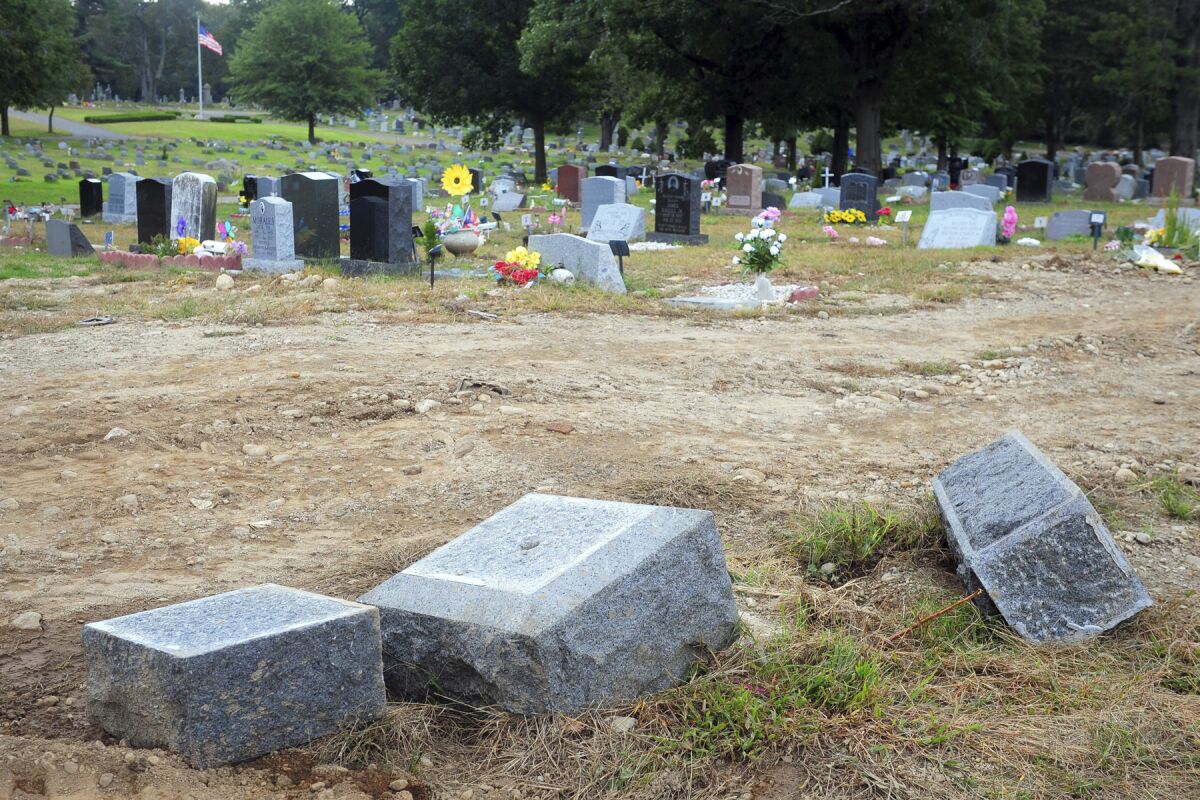 FILE - In this Oct. 2, 2018 file photo, toppled headstones rest on the ground in Park Cemetery in Bridgeport, Conn. The former caretaker of the cemetery is facing a new charge of embezzling more than $60,000 from the cemetery. Dale LaPrade, 66, was charged with first-degree larceny on Sept. 10 after a forensic audit discovered the theft of funds from Park Cemetery in Bridgeport between 2016 and 2018. (Ned Gerard/Hearst Connecticut Media via AP)