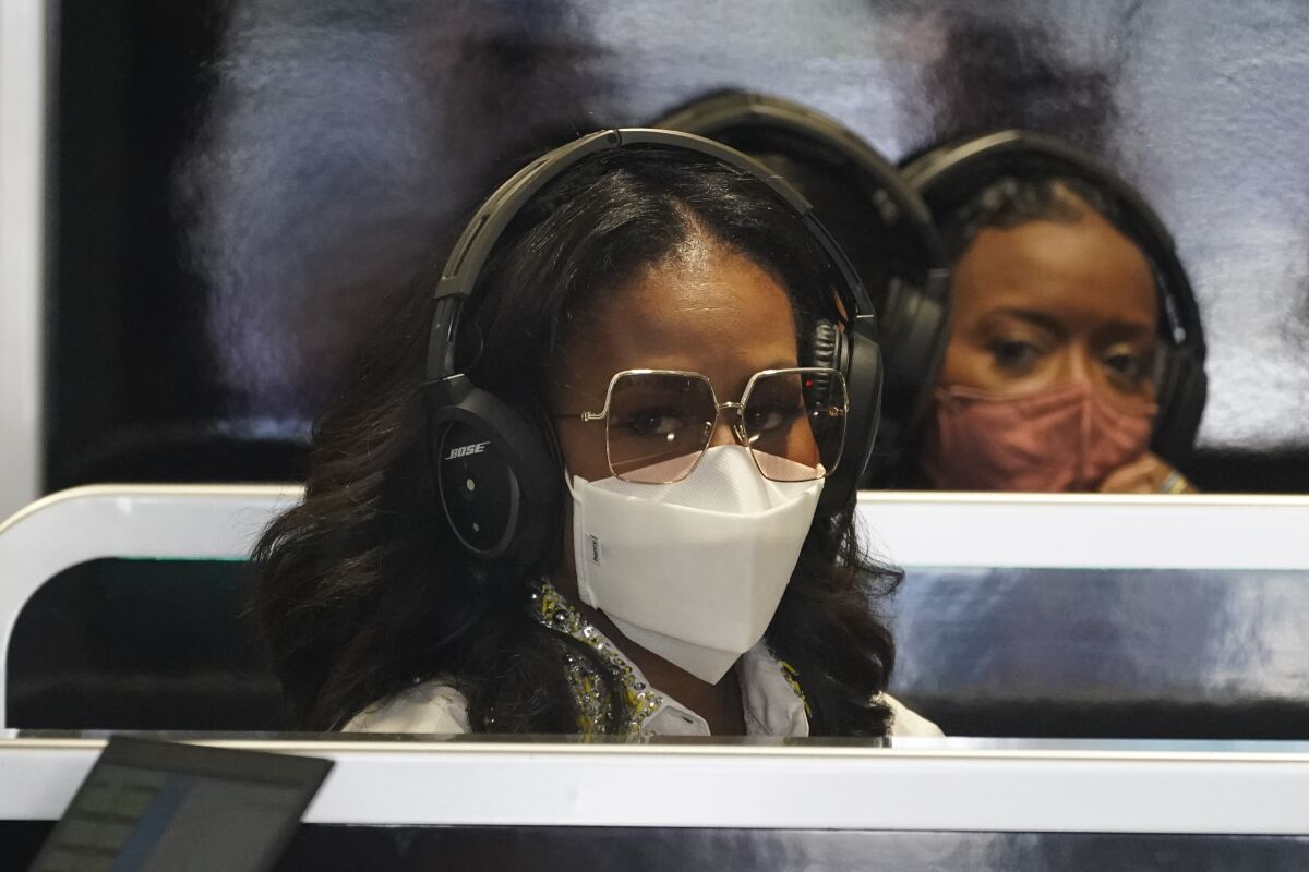 Former First Lady Michelle Obama, left, sits in the Mercedes team garage before the third practice session for the Formula One Miami Grand Prix auto race at the Miami International Autodrome, Saturday, May 7, 2022, in Miami Gardens, Fla. (AP Photo/Darron Cummings)