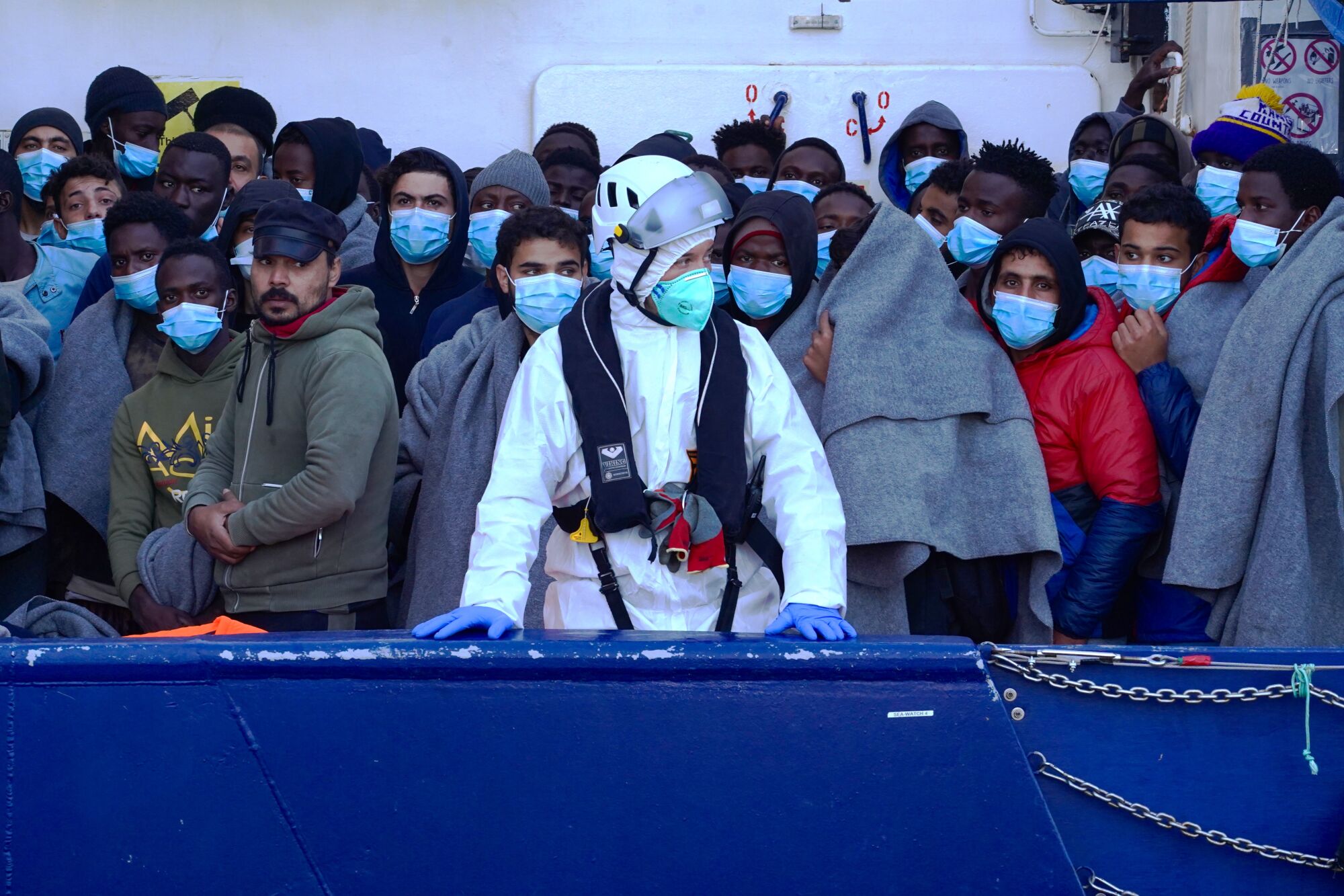 People in masks wait on a boat.