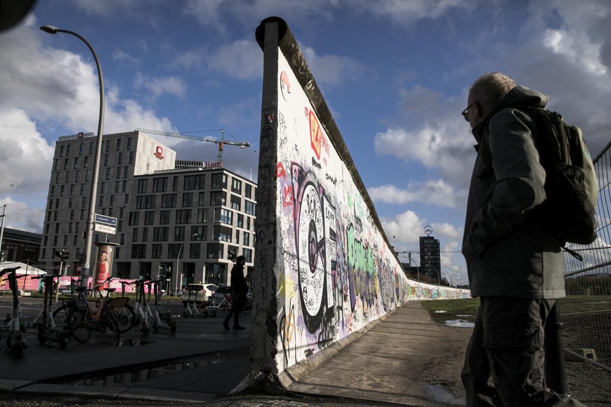 Tourists in Germany stand at a former section of the Berlin Wall called the East Side Gallery .