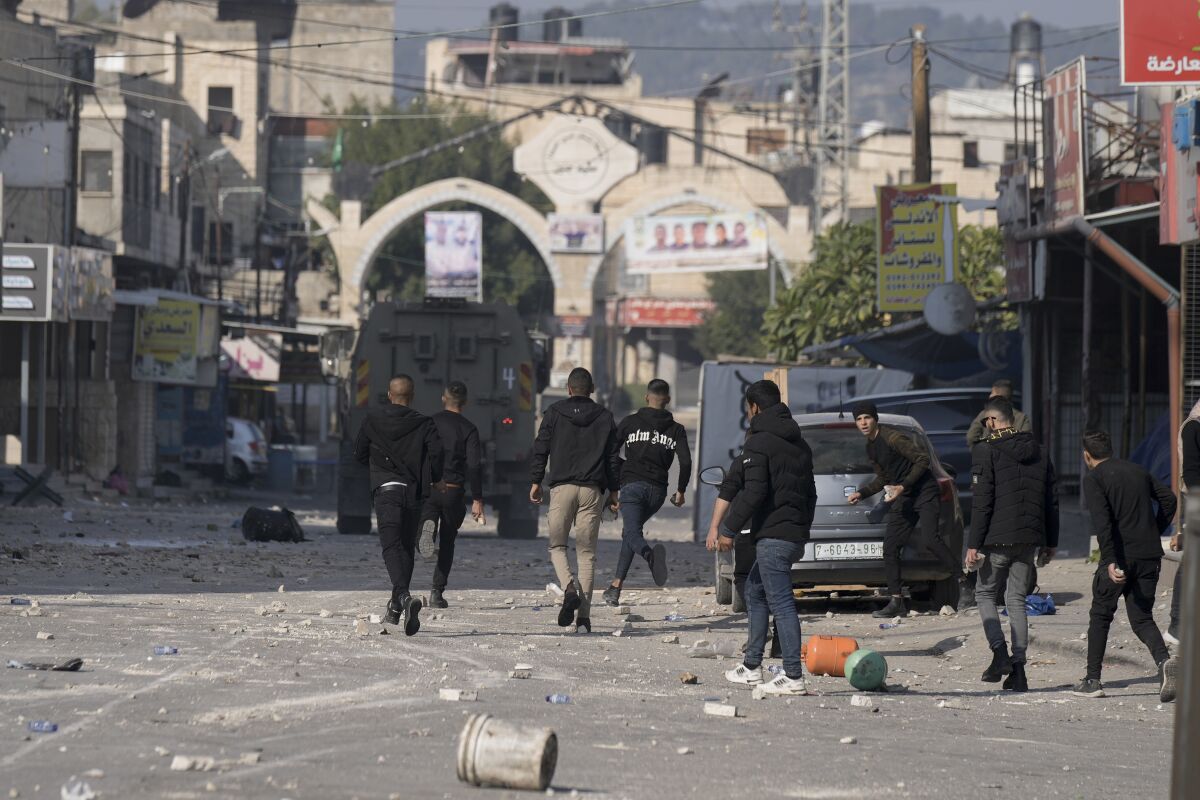 People walk in a street with debris