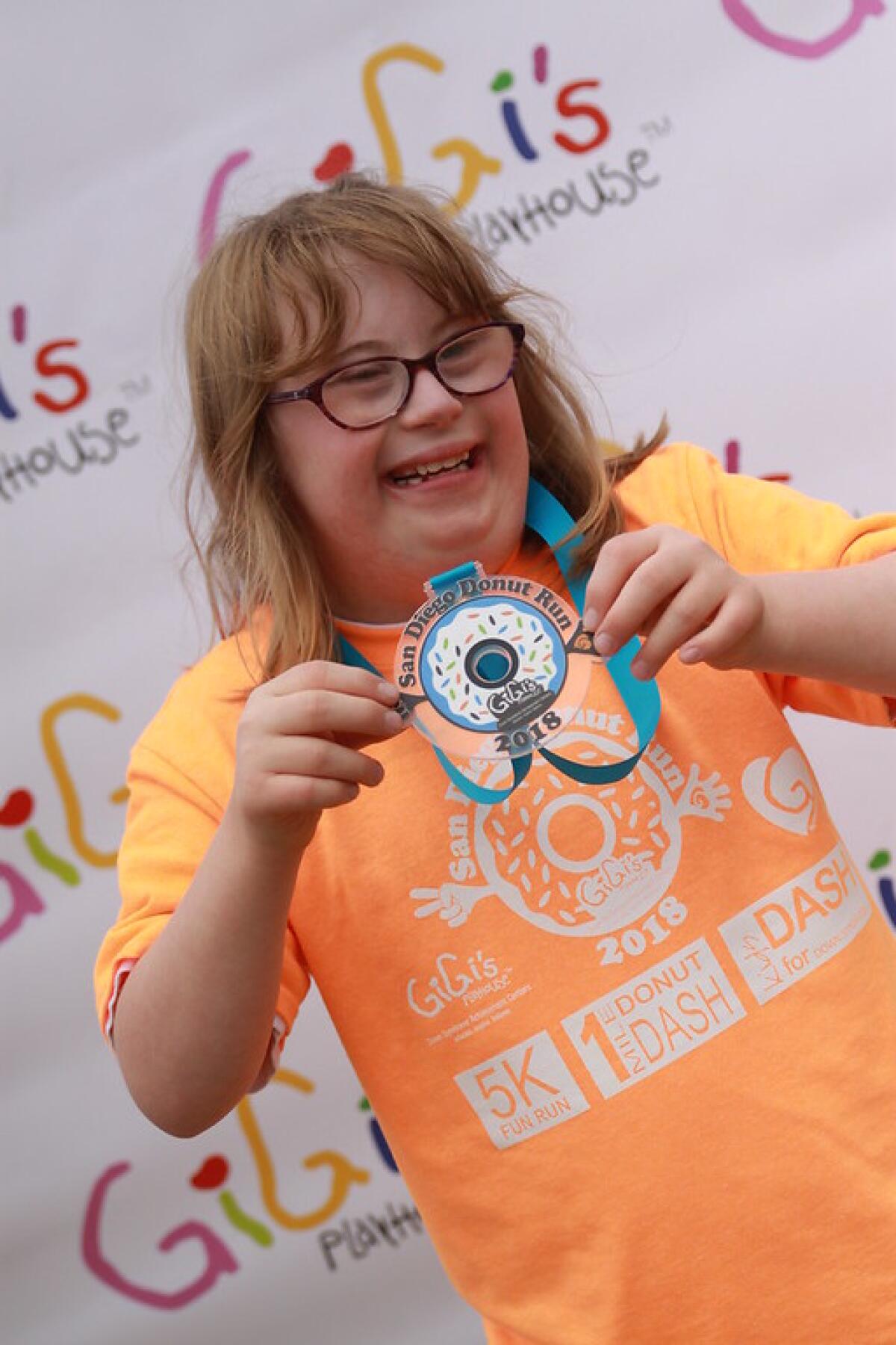 A participant of the inaugural San Diego Donut Run poses with her medal in 2018