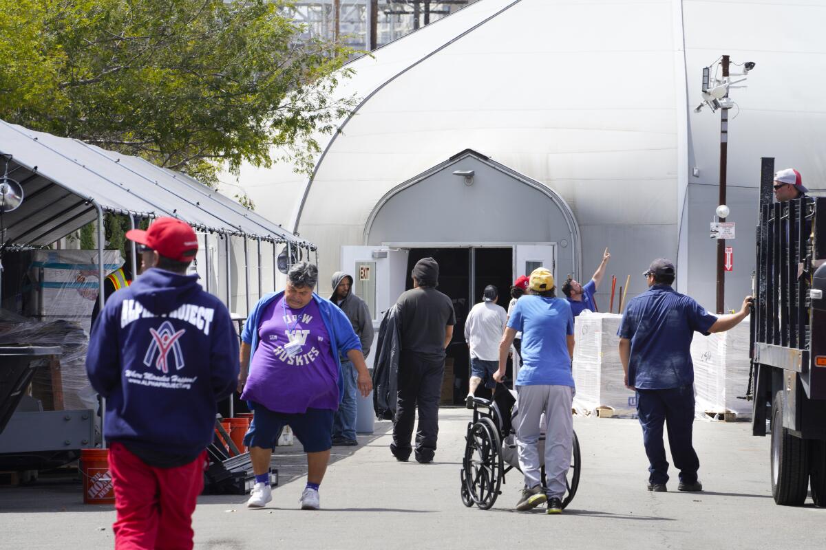 Residents and staff of Alpha Project's downtown tent in San Diego return to the shelter Wednesday.
