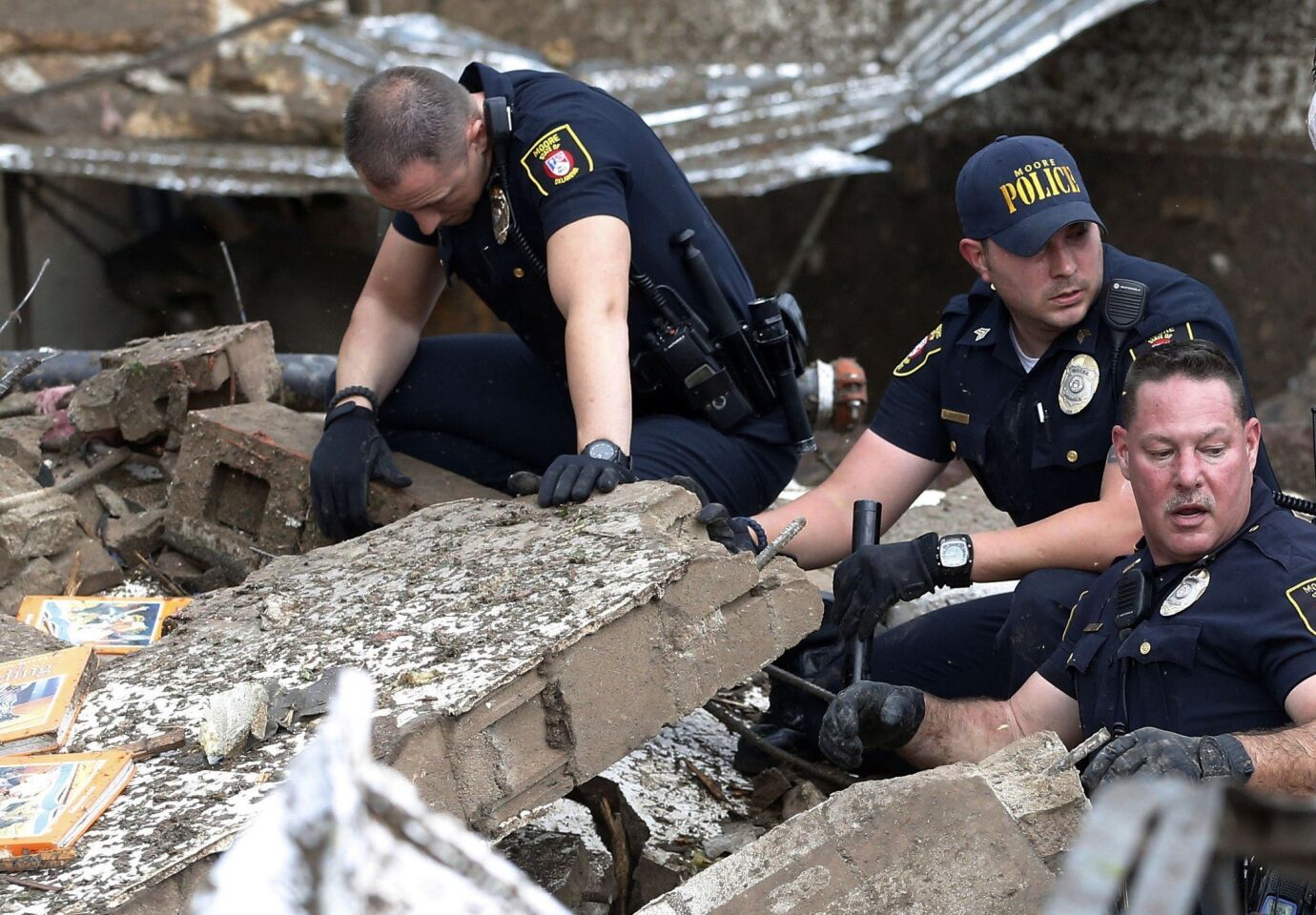 Moore police dig through the rubble of Plaza Towers Elementary School after a tornado in Moore, Okla.