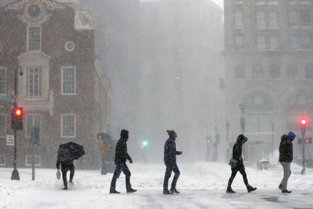 People cross a snowy street in Boston. 