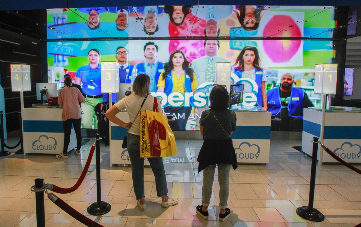 While viewing a "Superstore"-themed check-in desk, hotel guests wait in line to check in at the Hard Rock Hotel during Comic-Con on July 18, 2019, in San Diego.