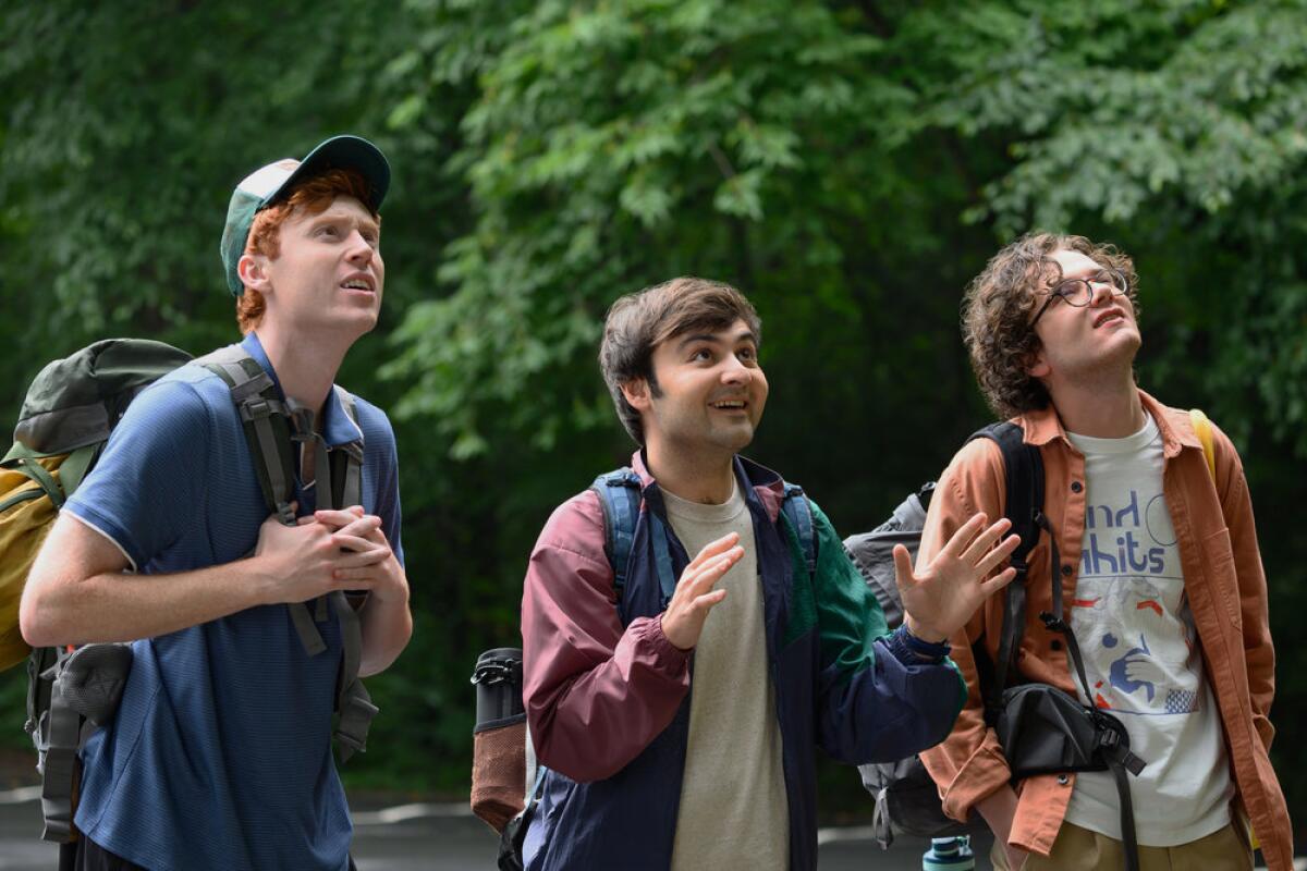 Three men looking up excitedly at something in a tree as they search for treasure in the woods.