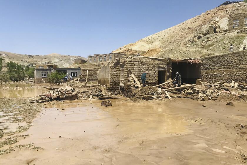 Afghan men collects their belongings from their damaged home after heavy flooding in Ghor province in western Afghanistan Saturday, May 18, 2024. Flash floods from heavy seasonal rains in Ghor province in western Afghanistan killed dozens of people and dozens remain missing, a Taliban official said on Saturday, adding the death toll was based on preliminary reports and might rise. (AP Photo/Omid Haqjoo)