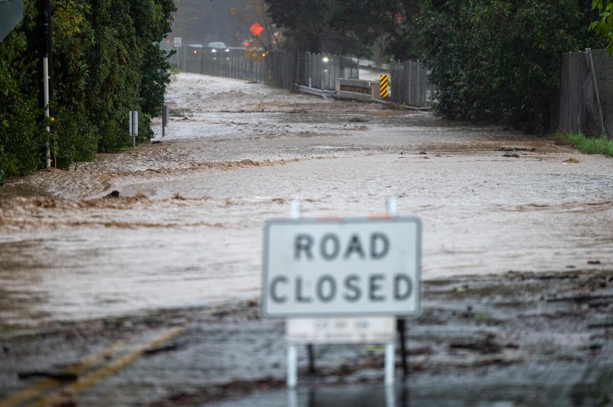 A flooded street with a 'road closed' sign in front of it