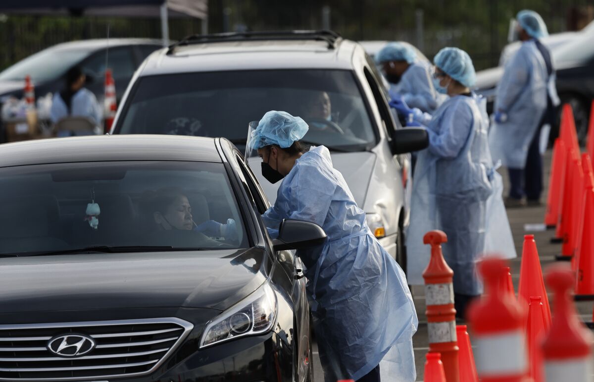 Healthcare workers administer COVID-19 tests at a drive-through testing site in Norwalk