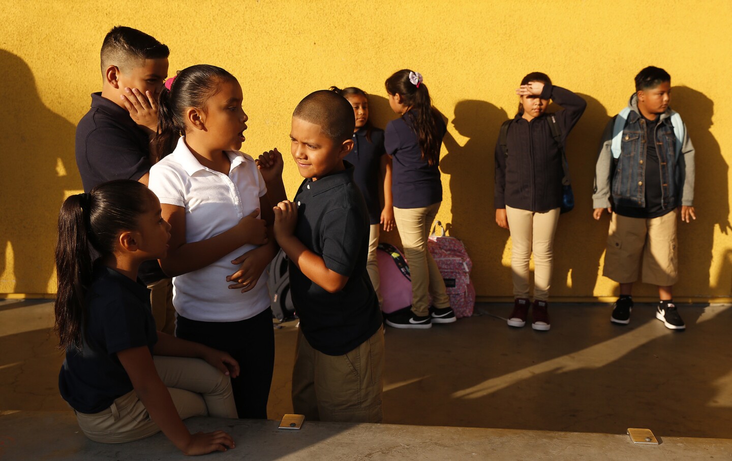 Leslie Toriz, in white shirt, plays with her cousin Alex Toriz as the third-graders wait for doors to open on their first day back at Dolores Huerta Elementary School in Los Angeles on Tuesday.