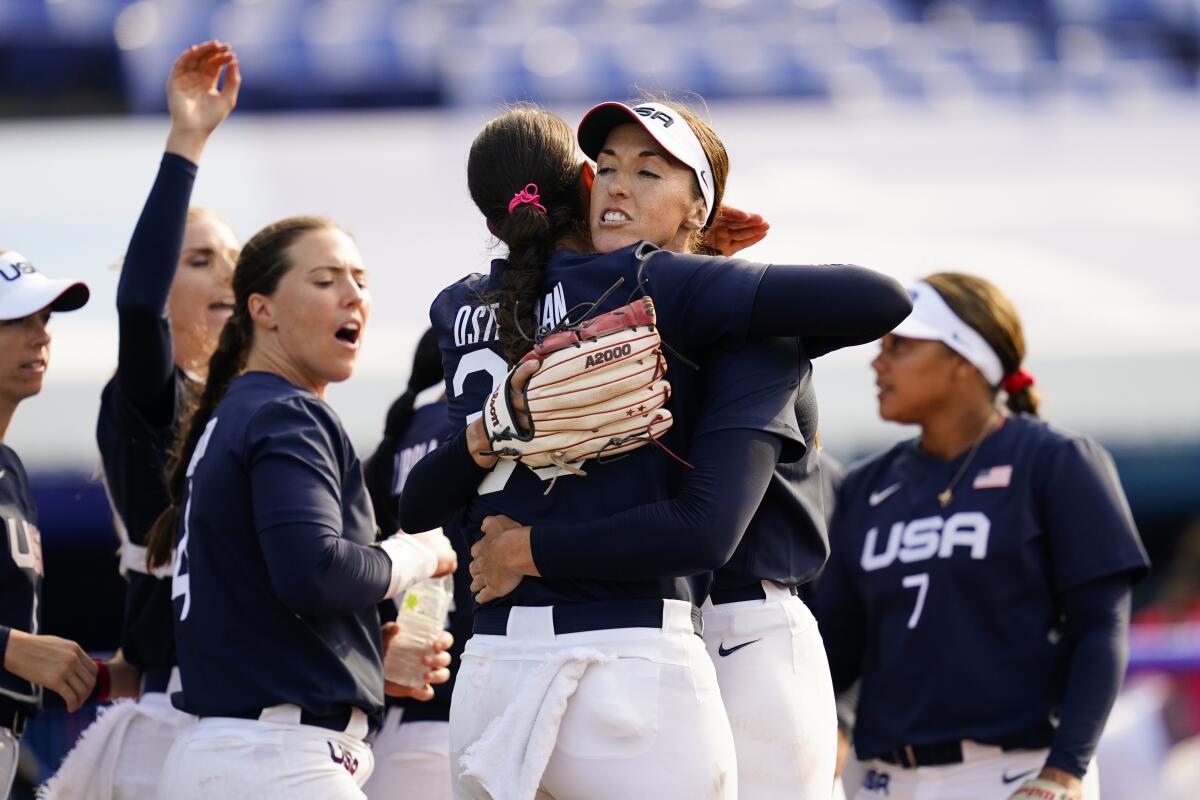 Monica Abbott and Cat Osterman hug as other players celebrate.